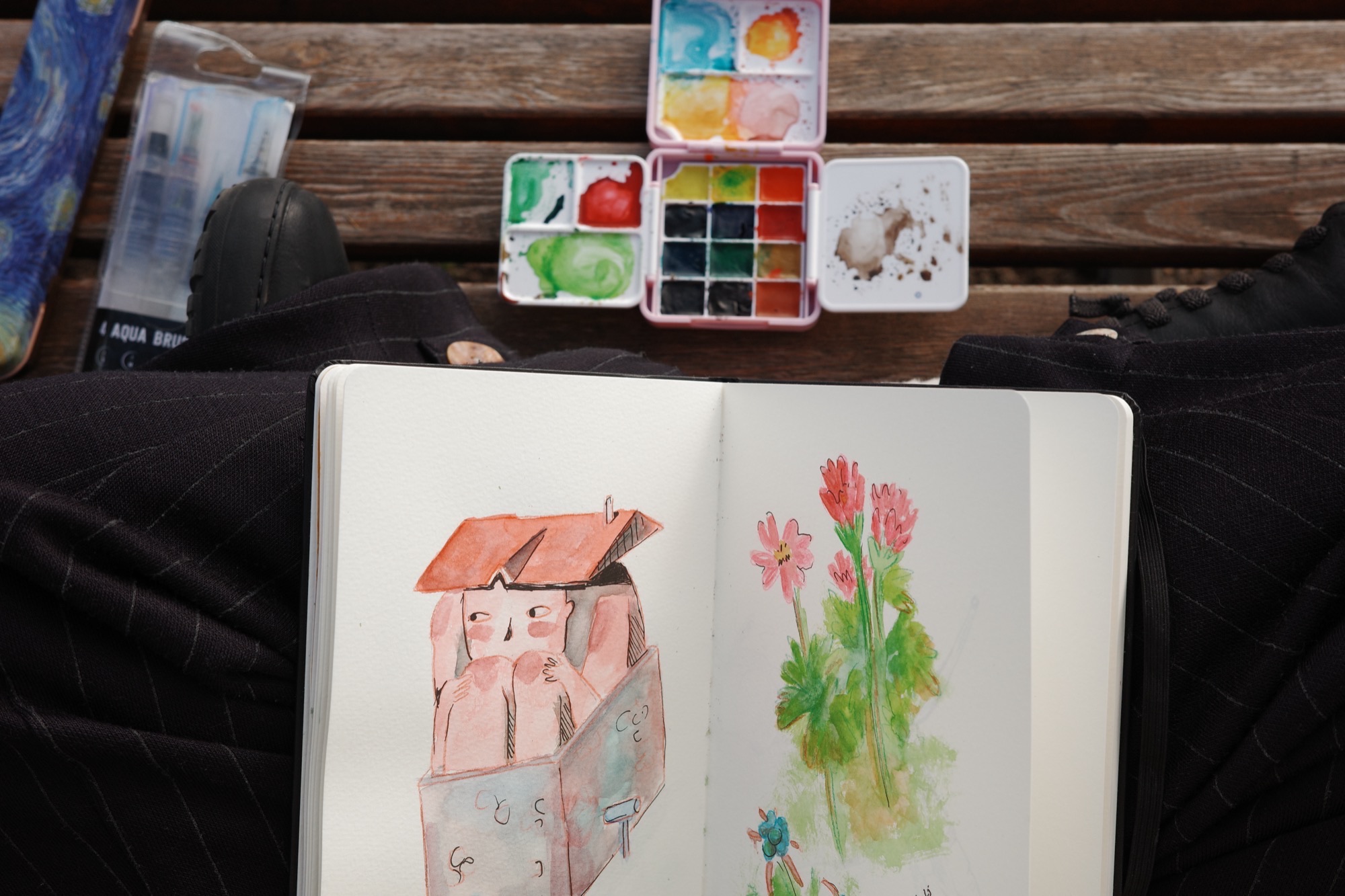 Watercolour kit and open sketchbook on a bench
